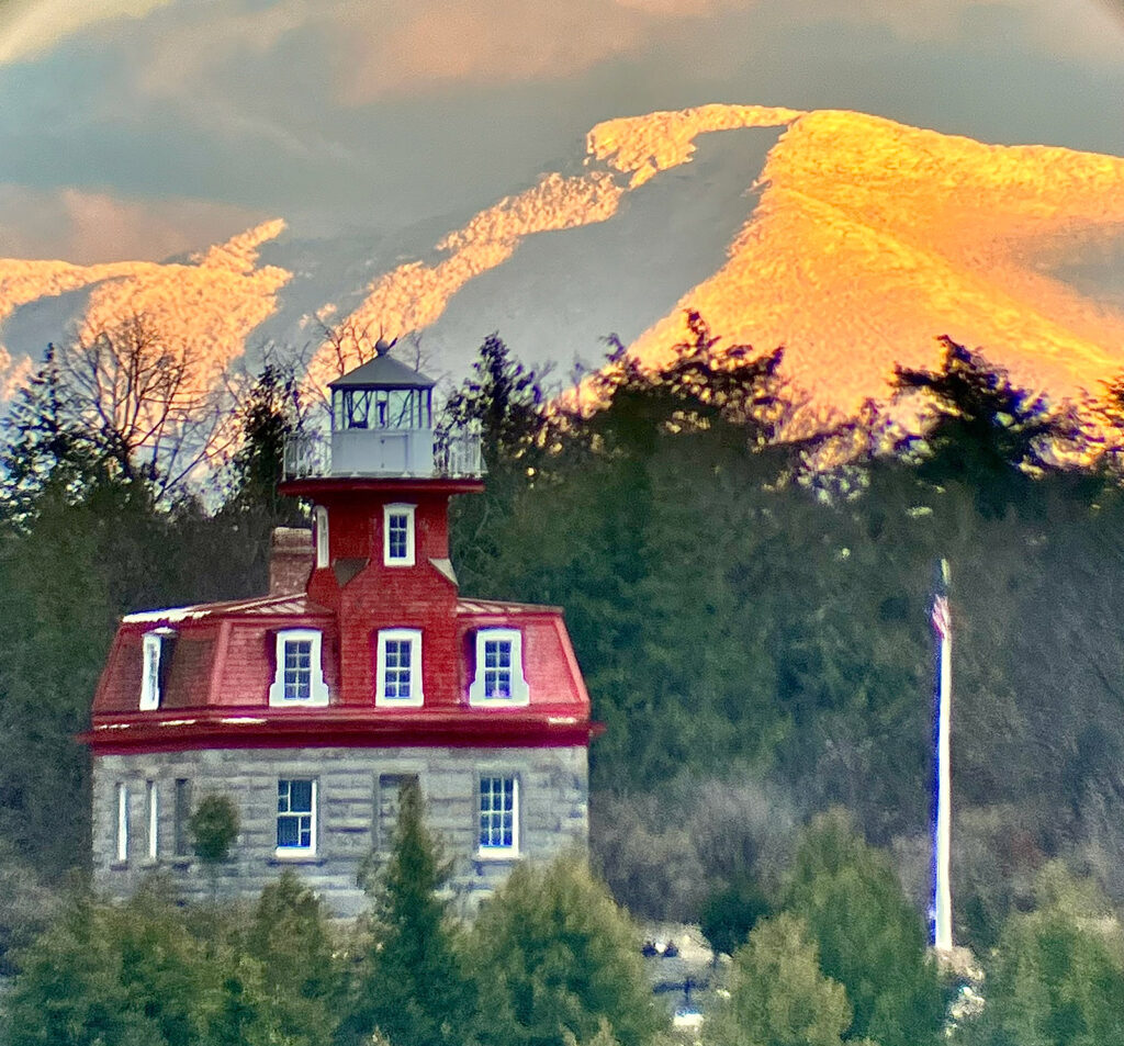 Valcour Island Lighthouse with a view of mountains in the background.